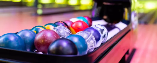 Un distributeur de boules de bowling en avant plan avec les allées en arrière plan