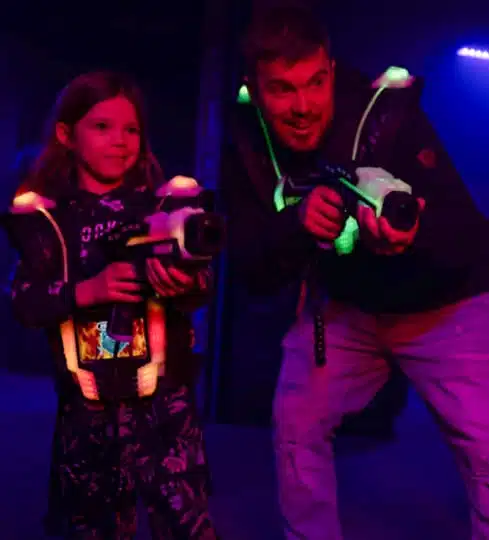 Un adulte et une enfant jouant au lasertag dans le vif de l'action
